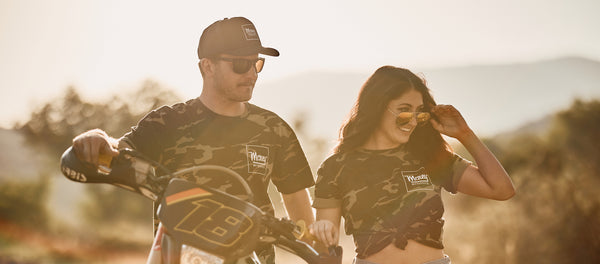 two friends standing with dirtbike in camo short sleeve shirt for men and women