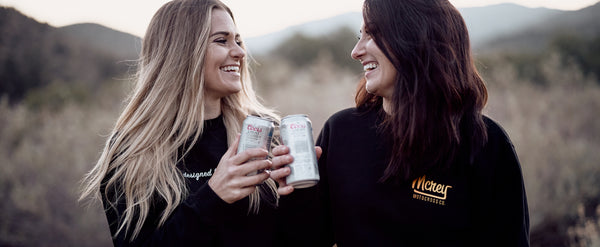 two sisters in the desert drinking beer and laughing wearing mcrey motocross apparel for women