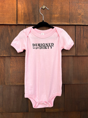 Light pink baby onesie with the words Designed to get Dirty® written on the front chest in black