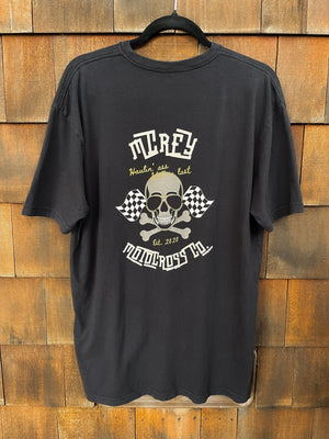 Black unisex short sleeve shirt. It features a skull wearing aviators with two checkered flags and the words "Haulin' ass, Still in Last" on the back.