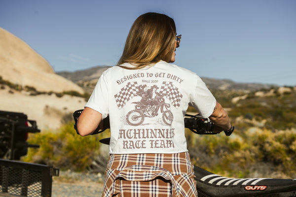 Woman wearing a cream shirt that says "Designed to get dirty.® McHunnies Race Team."