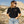 Load image into Gallery viewer, Woman wearing a black t-shirt with a logo and sunglasses, standing in a desert landscape.
