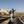Load image into Gallery viewer, Person standing on train tracks with arms outstretched in a desert landscape
