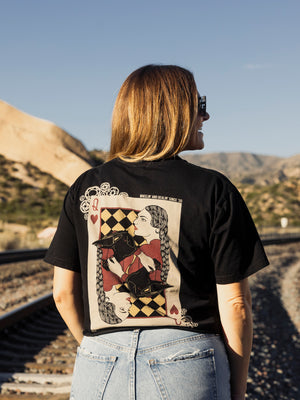 Person wearing a black t-shirt with a graphic design, standing outdoors with mountains in the background.