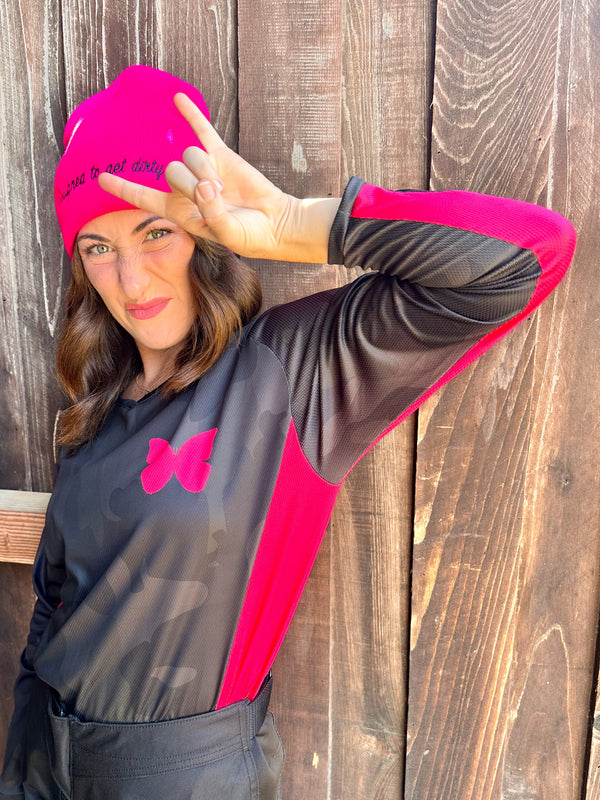 Woman wearing a black and pink outfit with a matching beanie against a wooden background