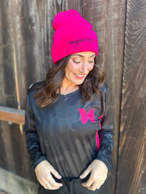 Woman wearing a dark grey camo dirt bike jersey with hot pink accents.