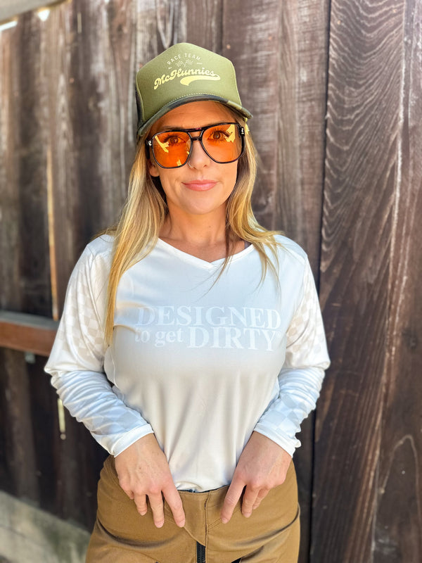 Woman wearing a off-white dirt bike jersey with checkered sleeves and the words "Designed to get dirty®" across the front.