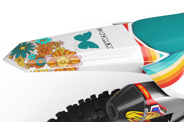 Honda CRF 250X with a 70's-inspired dirt bike graphics kit. There are lots of turquoise, orange and yellow flowers giving a flower power vibe.