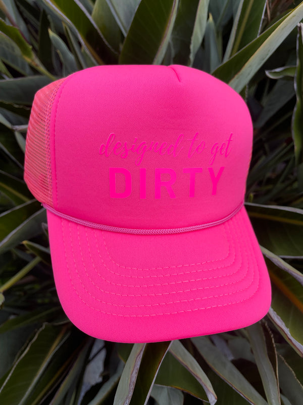 Neon pink trucker hat with neon pink writing that says designed to get dirty