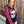Load image into Gallery viewer, Woman wearing a black shirt with a skull design and red and black checkered sleeves against a wooden fence.
