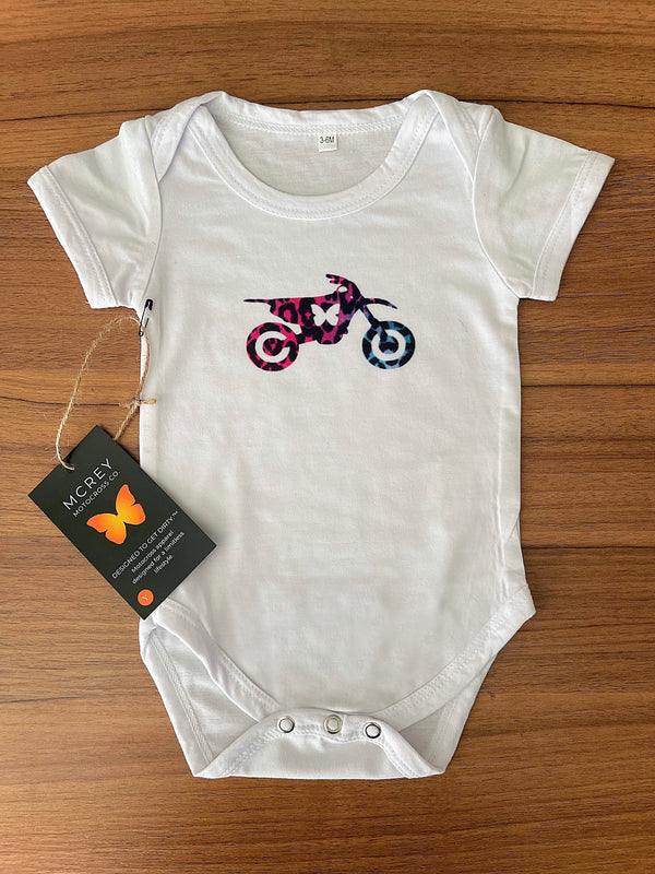 white baby onesie with a multi-colored leopard print butterfly dirt bike on it