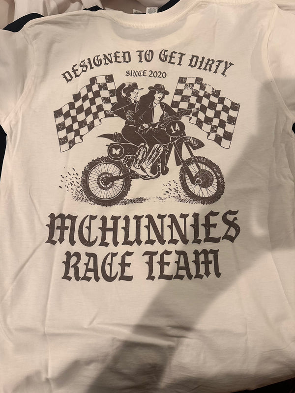 White t-shirt with graphic design of two people on a motorcycle and text 'Designed to Get Dirty Since 2020 McHunnies Race Team'.