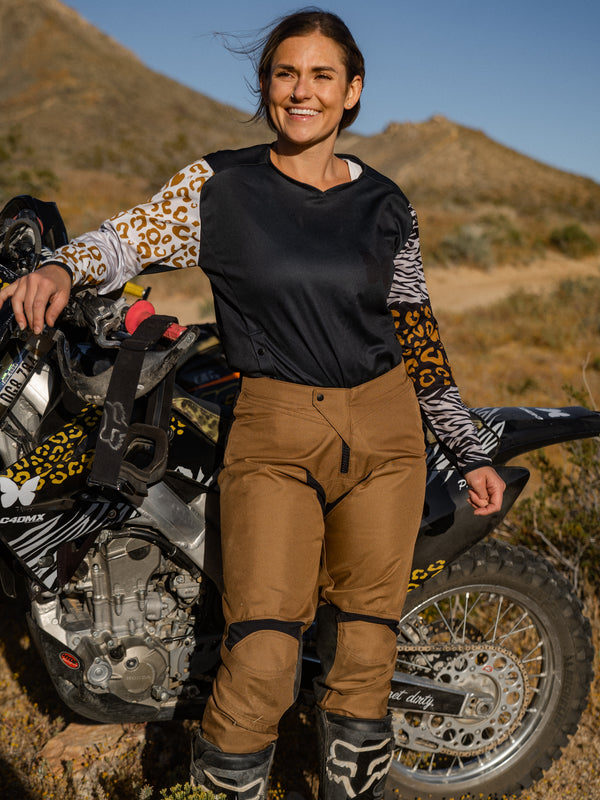 Woman wearing a pair of mocha and black dirt bike pants with an animal print jersey