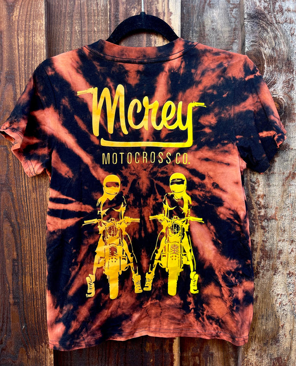 Women's tie-dyed black tee. On the back is MCREY MOTOCROSS CO logo above two girls sitting on dirt bikes.