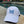 Load image into Gallery viewer, Youth white baseball-style cap with a blue-blend butterfly stitched on the front sitting next to a pool.
