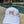 Load image into Gallery viewer, Youth white baseball-style cap with a rainbow butterfly stitched on the front sitting next to a pool.

